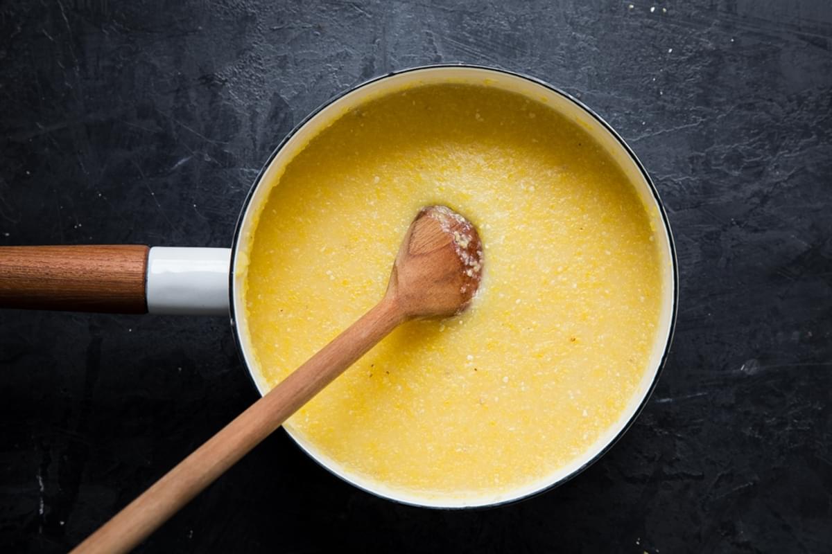 cooked polenta in a small pot with a wooden spoon