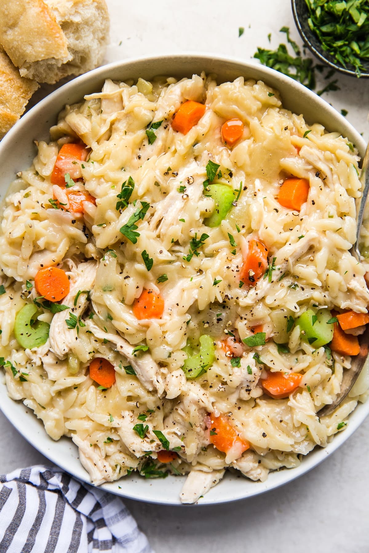 creamy Chicken Orzo Soup with carrots and celery in s bowl with a linen