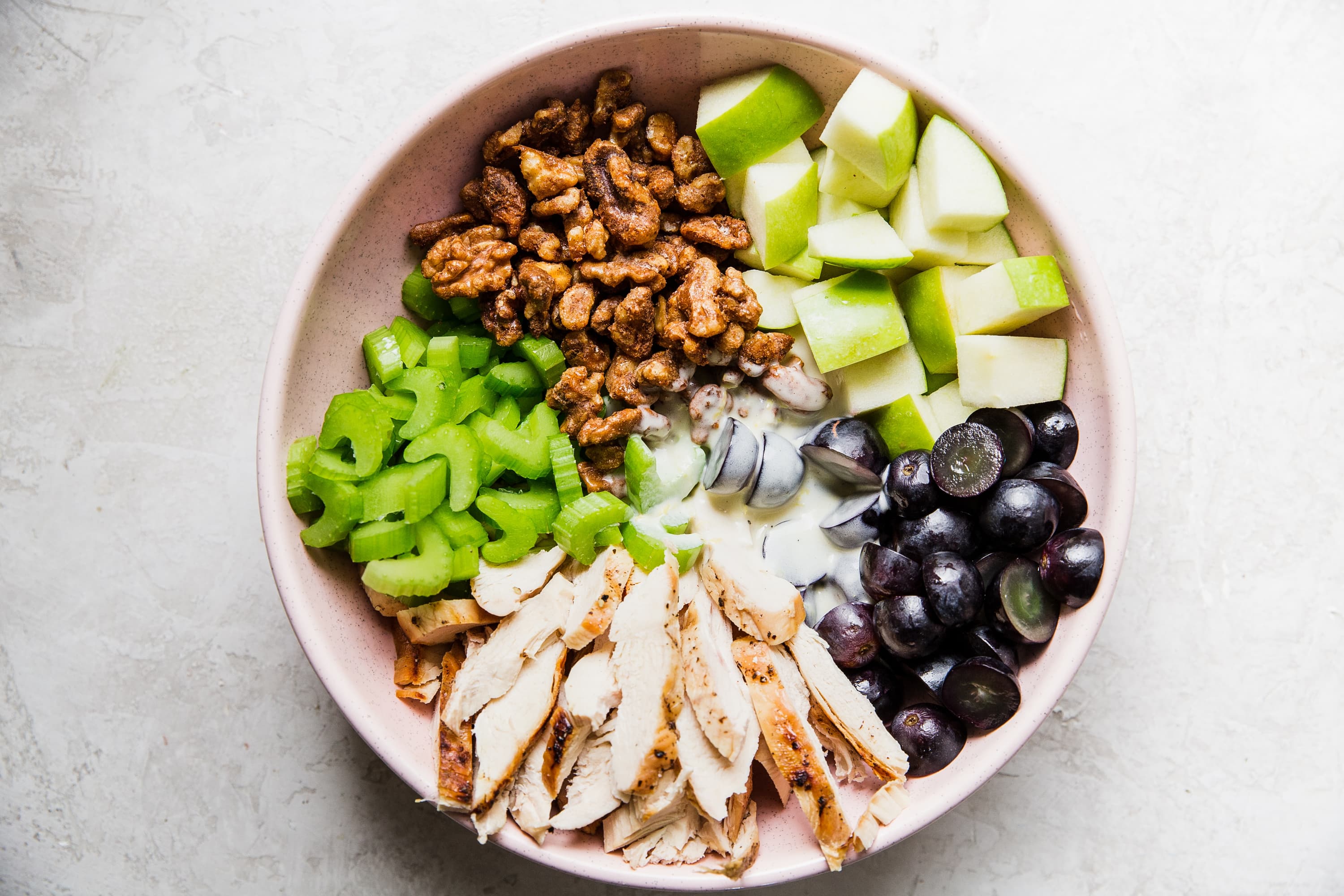 candied walnuts, grapes, apples, grilled chicken and celery in a bowl for a waldorf salad