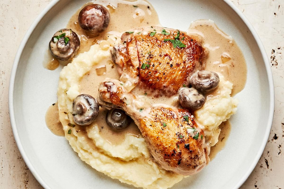 homemade chicken fricassee with mushrooms and onion served on top of classic mashed potatoes