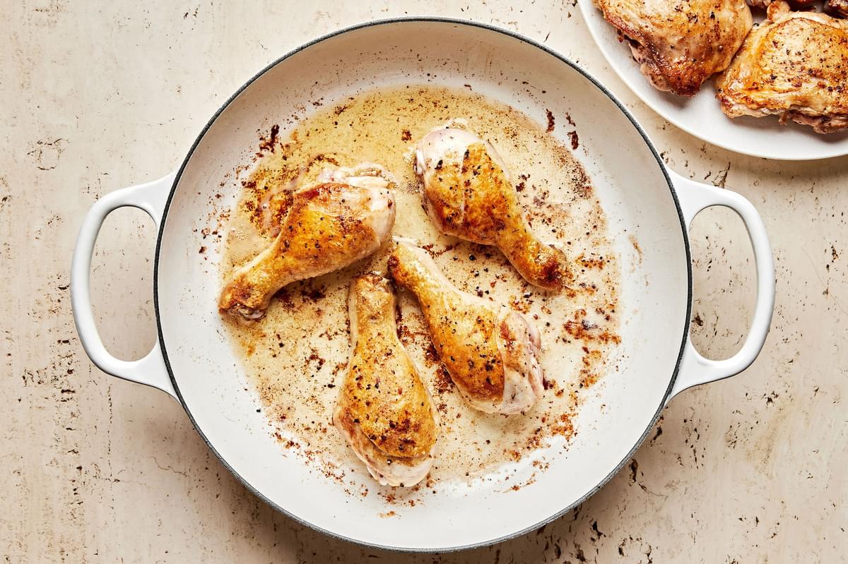 4 chicken drum sticks seasoned with salt and pepper cooking in melted butter in a skillet