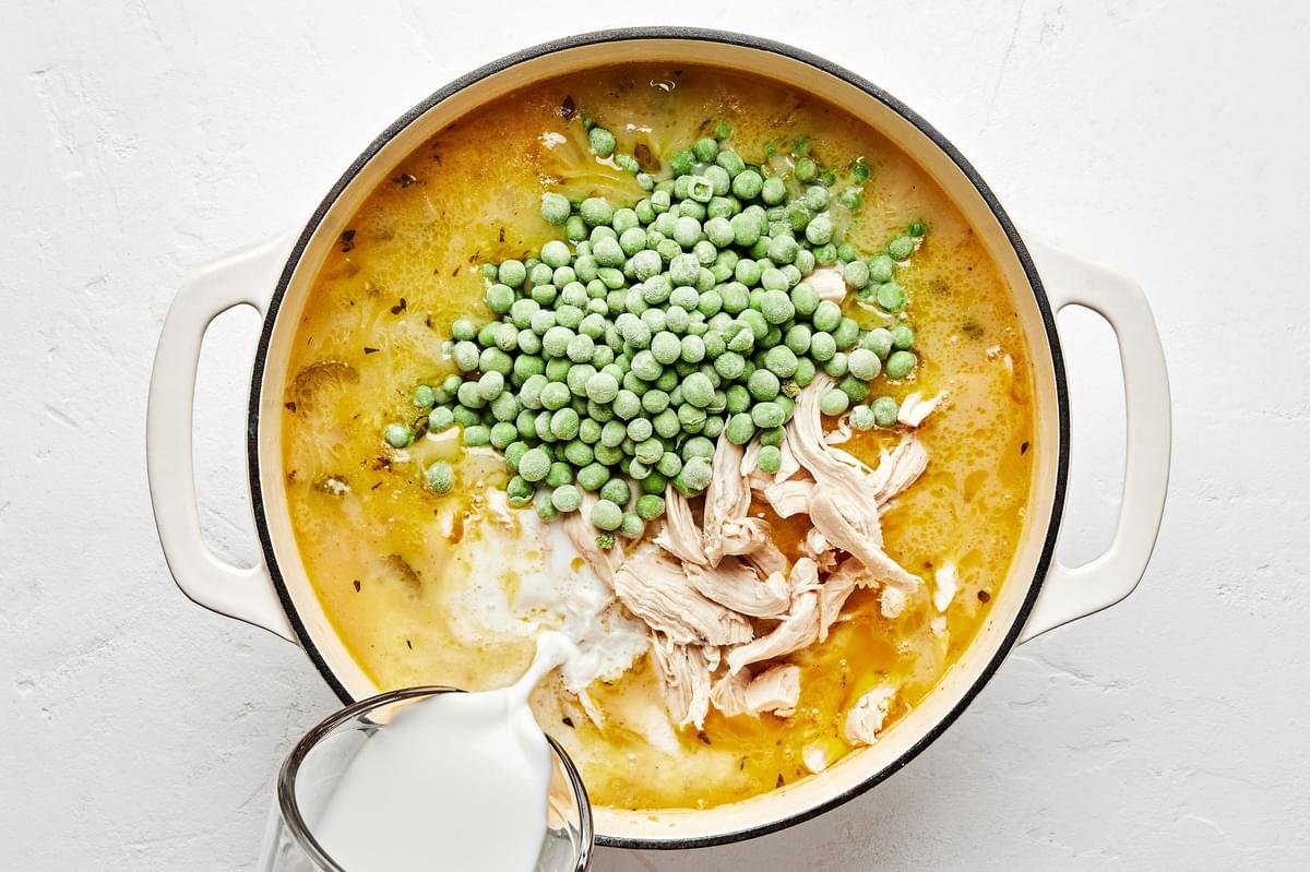 frozen peas, chicken, potatoes, spices, stock, butter, flour, carrots, celery, and onion cooking in a large pot