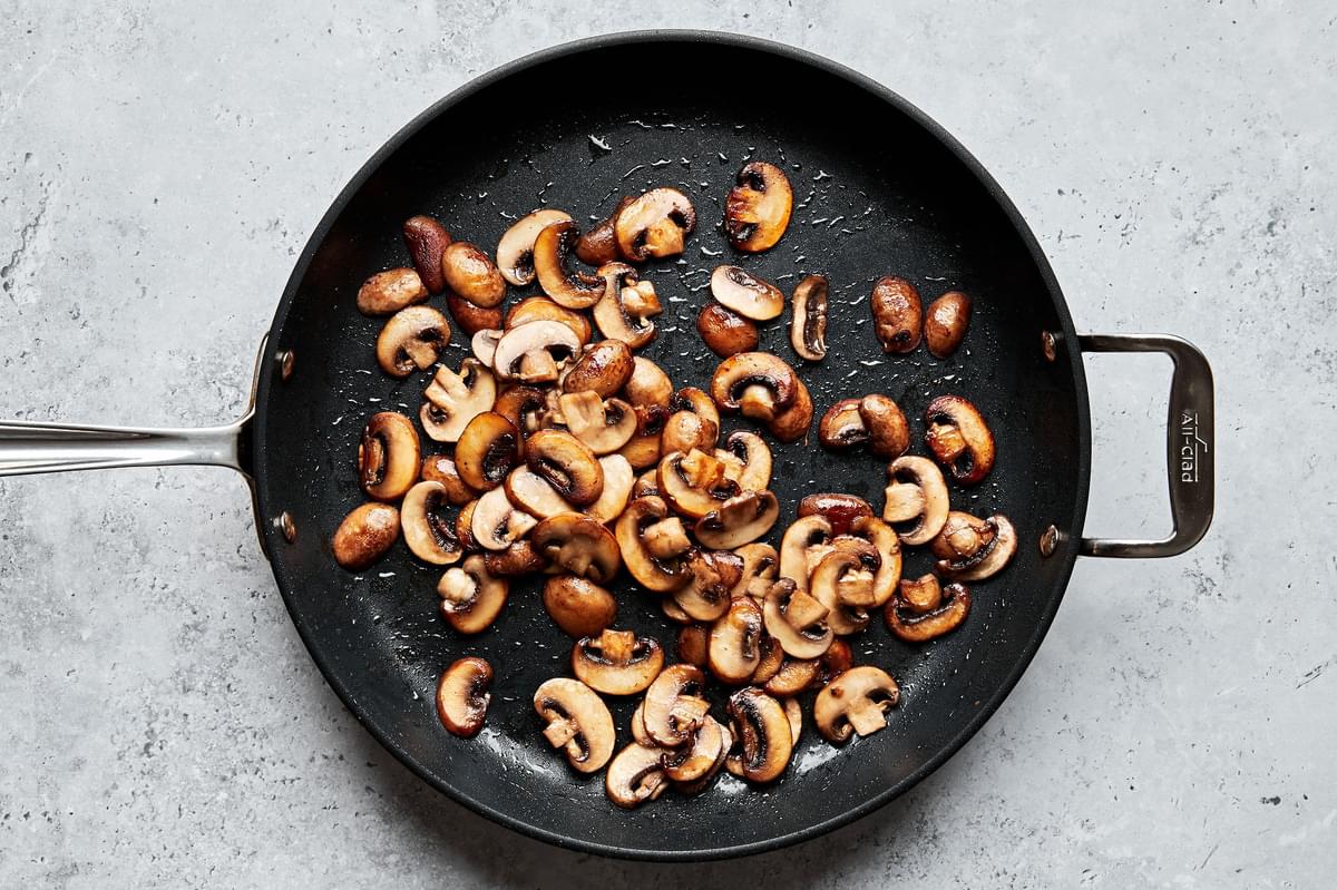 mushrooms cooking in olive oil and butter in a skillet