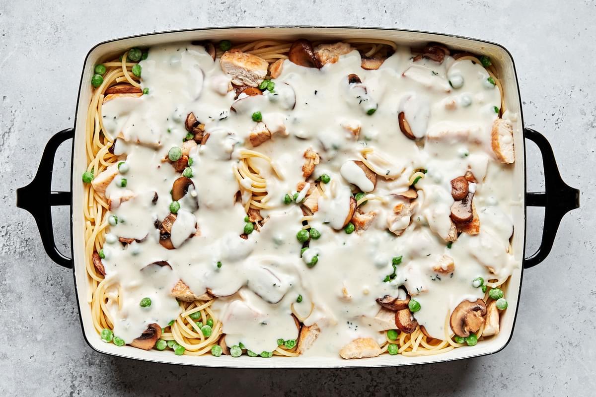 chicken, spaghetti noodles, peas and mushrooms covered in cream sauce in a 9x13 casserole dish