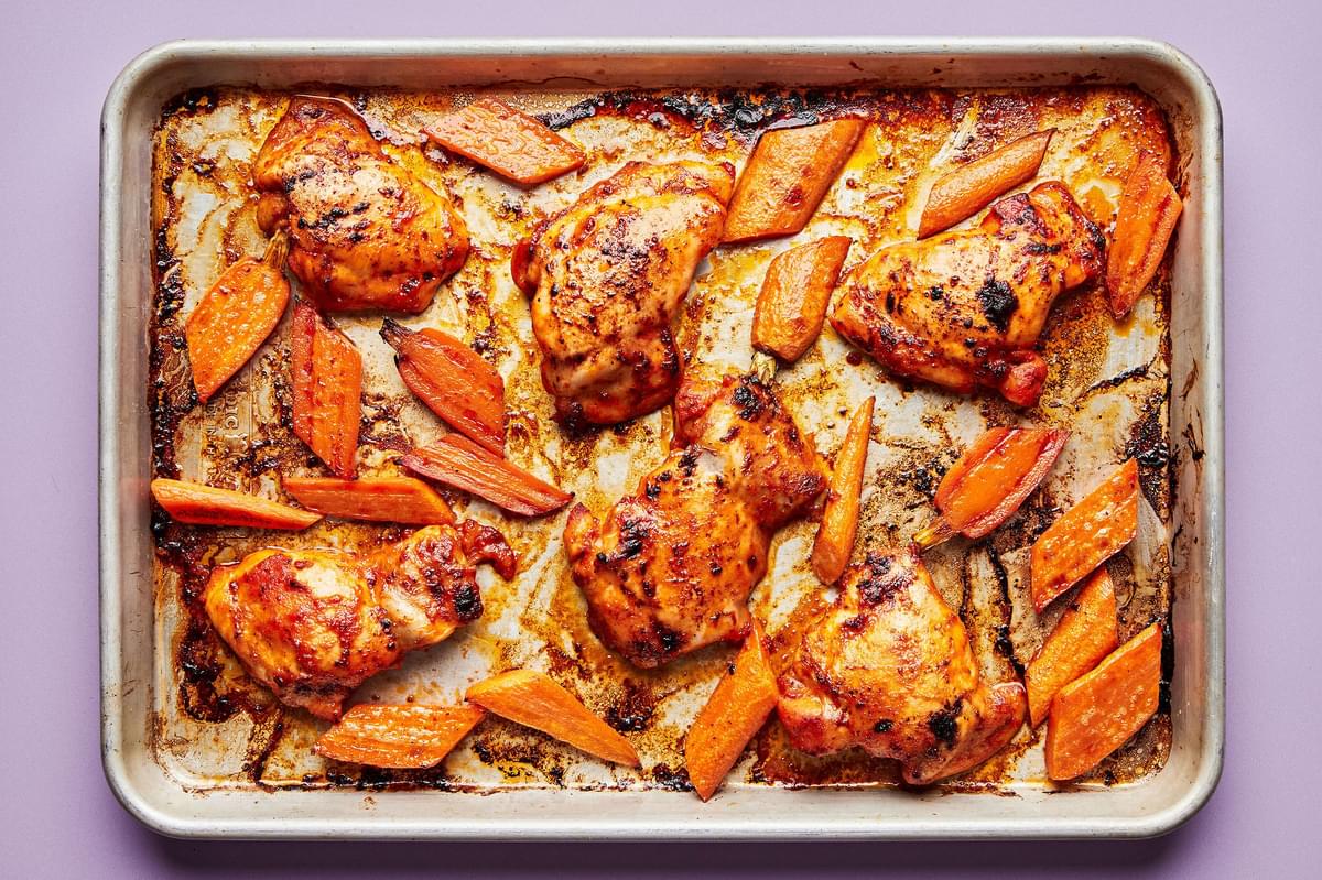 chicken in red pepper sauce and roasted carrots on a sheet pan
