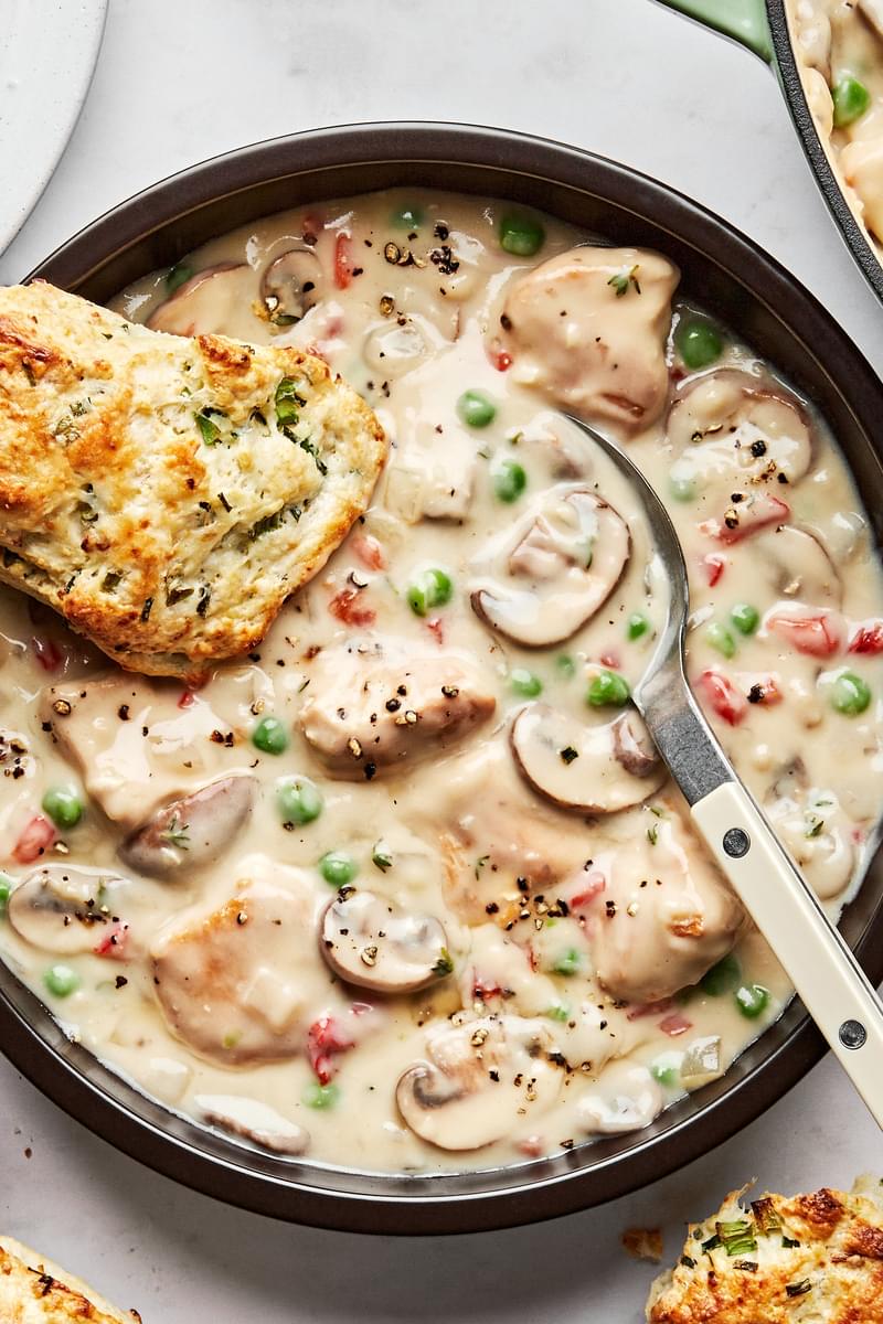 a bowl of Chicken à la King made with chicken, mushrooms and peas in a creamy white sauce served with onion chive biscuits