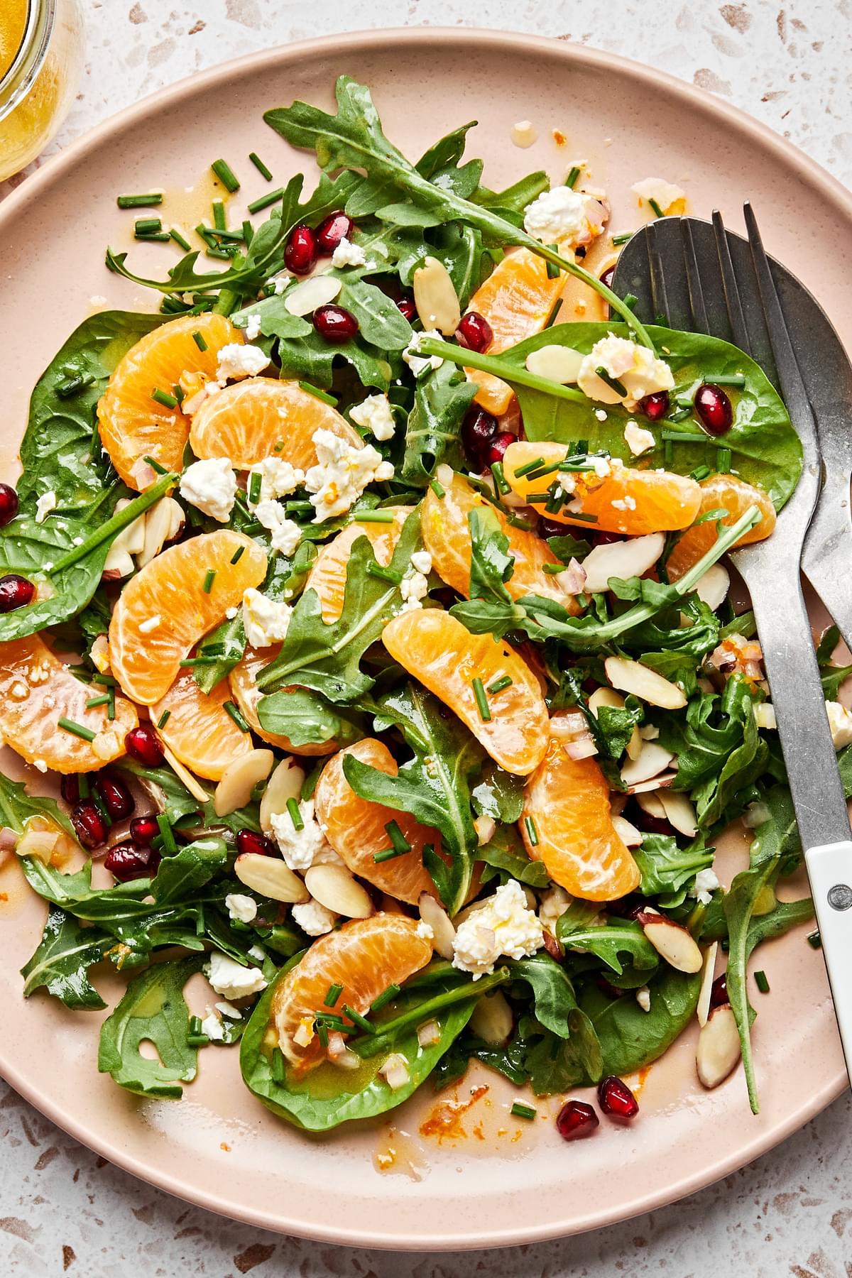 Christmas Salad on a platter made with spinach, arugula, feta, clementines, pomegranates, almond, chives and citrus dressing