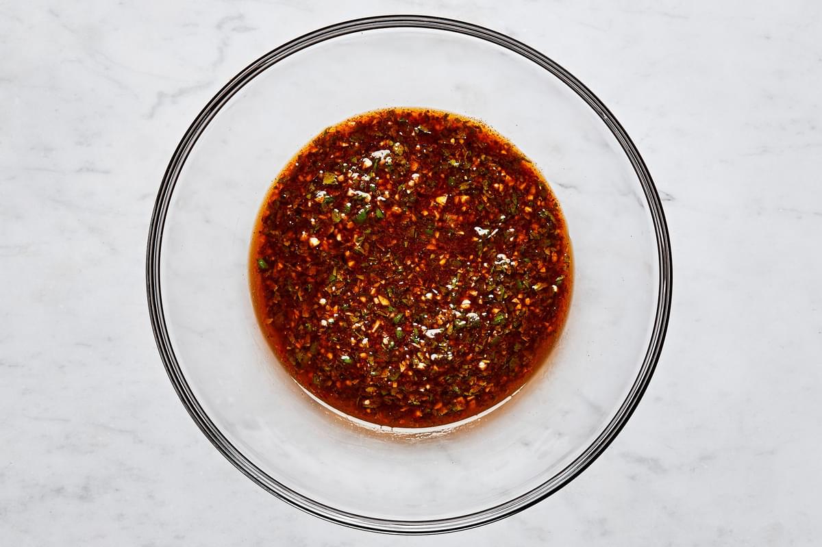 marinade made with olive oil, garlic, honey, lime zest, lime juice, cilantro, chili powder, salt, and pepper in a glass bowl