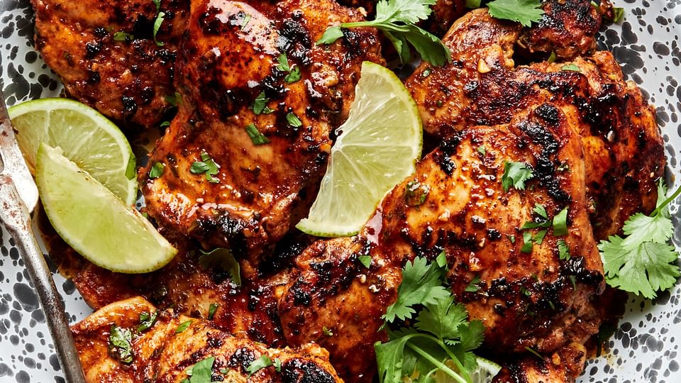 cilantro lime chicken thighs on a serving platter garnished with cilantro and lime wedges