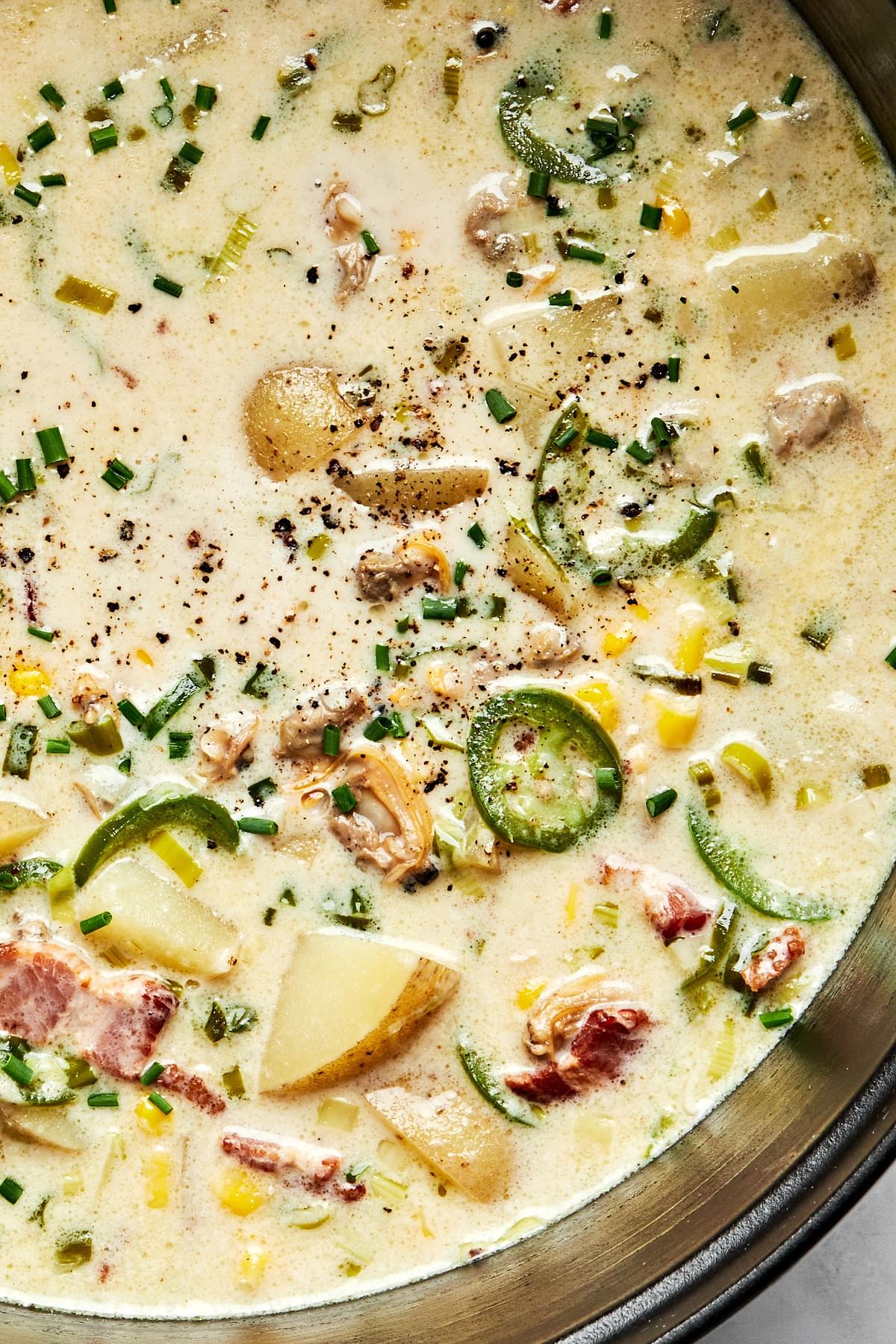 a pot of homemade clam chowder made with potatoes, scallions, bacon, jalapeños, corn, heavy cream and spices