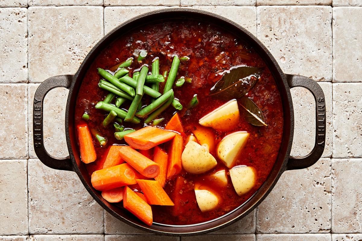 a pot of homemade classic beef stew with potatoes, green beans and carrots