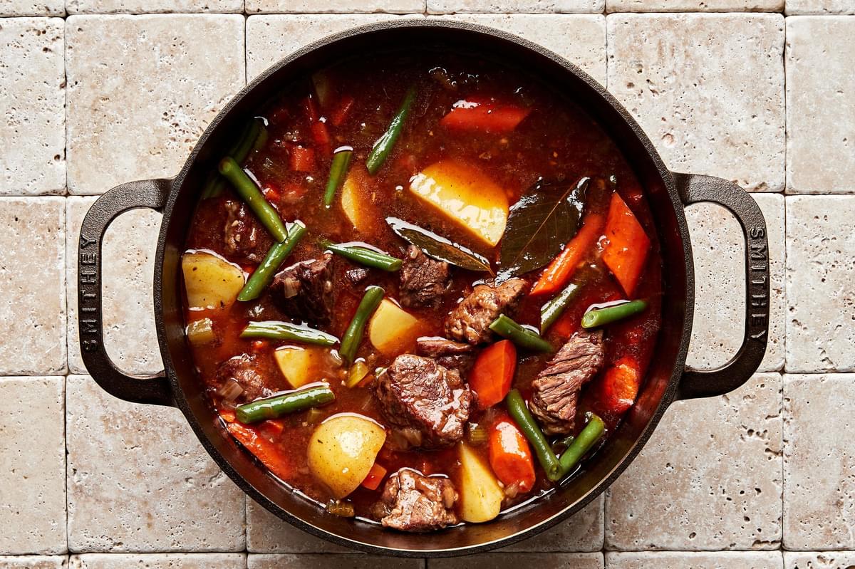 a pot of homemade classic beef stew with potatoes, green beans and carrots