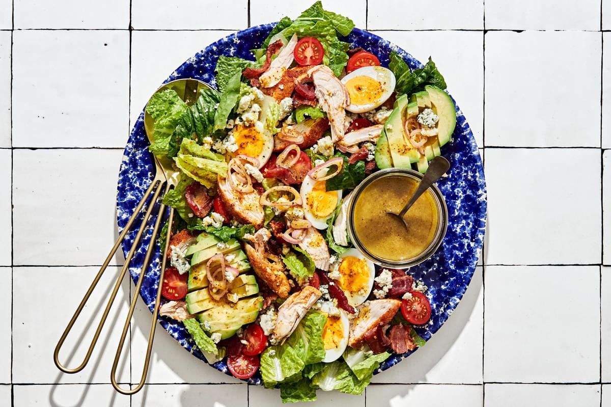 classic cobb salad made with romaine, chicken, hard boiled eggs, bacon, tomatoes, blue cheese, avocado & shallot vinaigrette