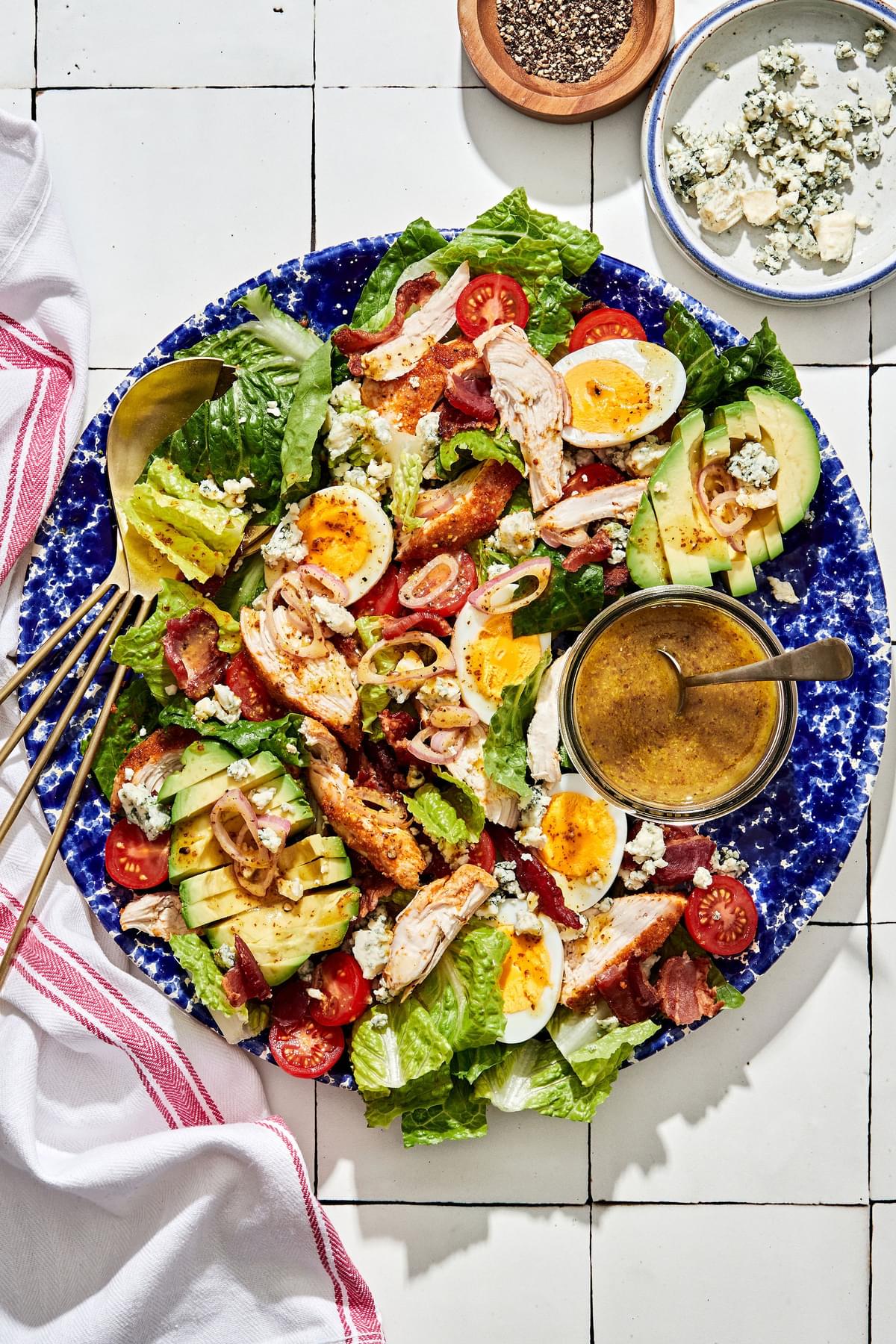 classic cobb salad made with romaine, chicken, hard boiled eggs, bacon, tomatoes, blue cheese, avocado & shallot vinaigrette