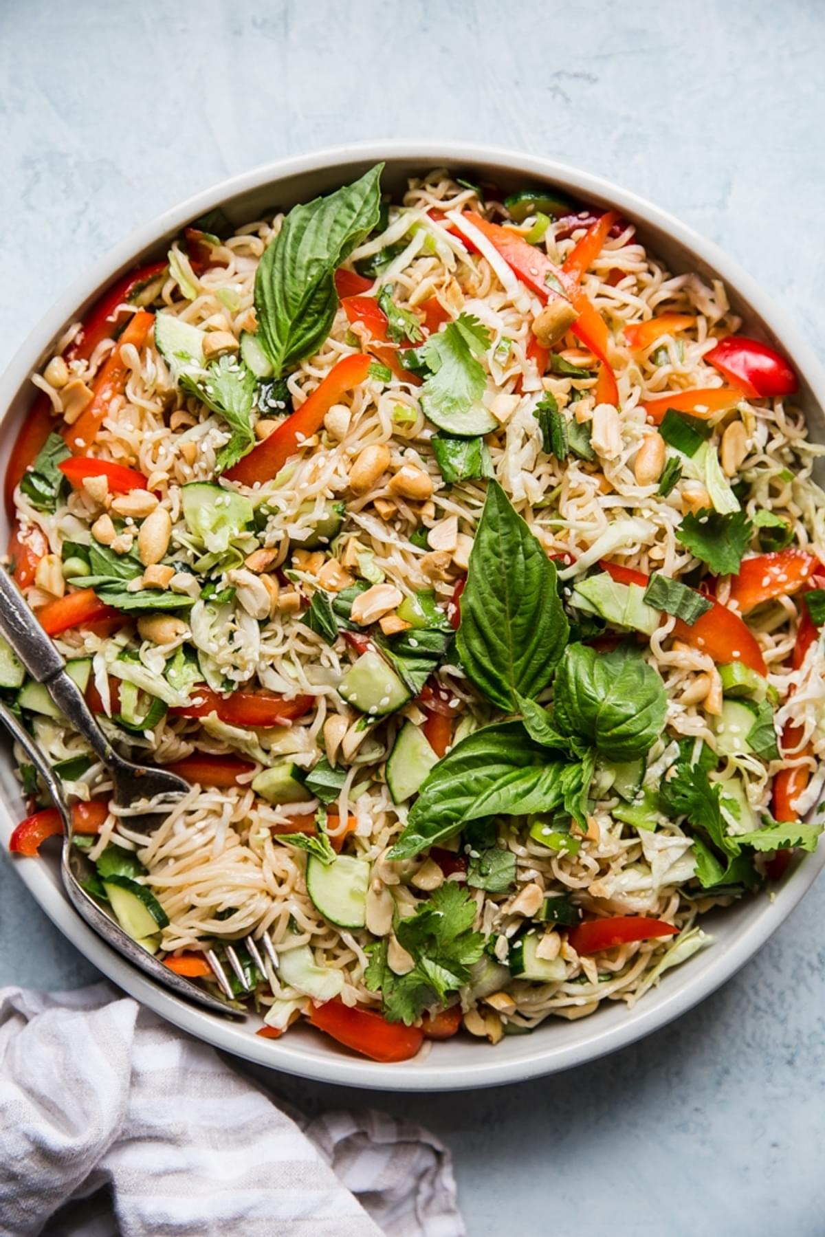 cold ramen salad in a bowl with basil, cucumbers, red bell peppers.