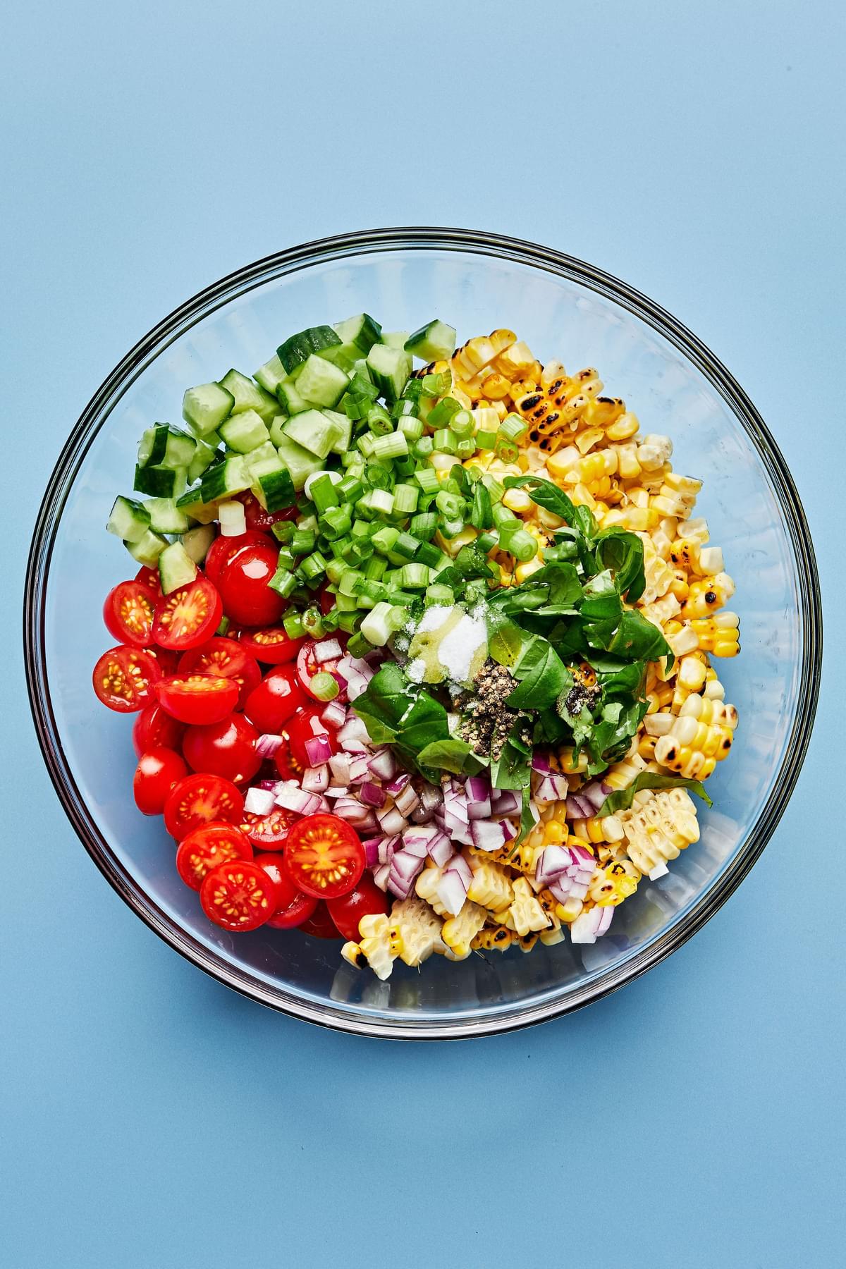 grilled corn kernels, tomatoes, cucumber, red onion, green onion, basil, lime juice, olive oil, honey, salt in a bowl