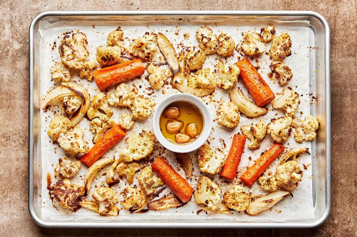 roasted cauliflower, carrots, onion and garlic on a baking sheet
