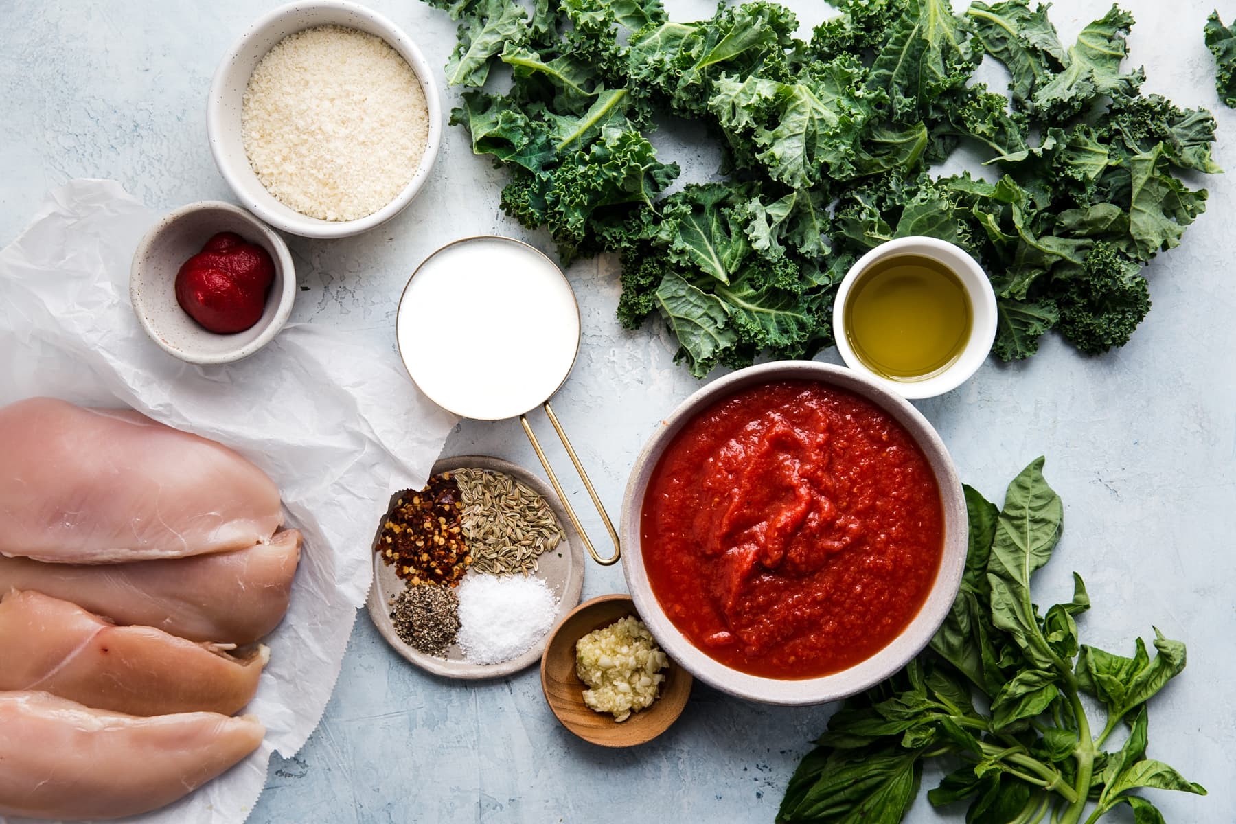ingredients laid out for Creamy Tomato Chicken Skillet Dinner cream, tomato paste, kale and basil