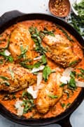 Creamy Tomato Chicken Skillet with kale and basil in a cast iron skillet with parmesan