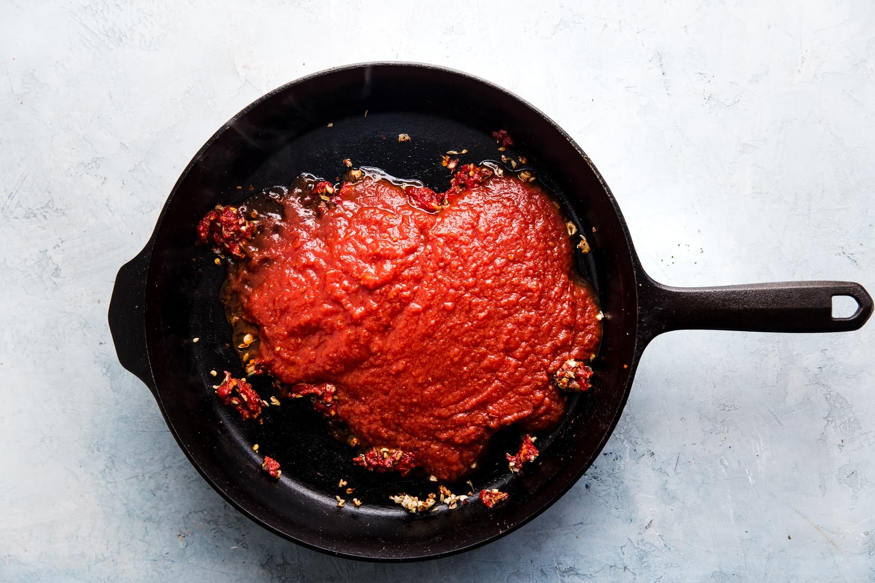 garlic, tomato paste and tomato sauce in a cast iron skillet