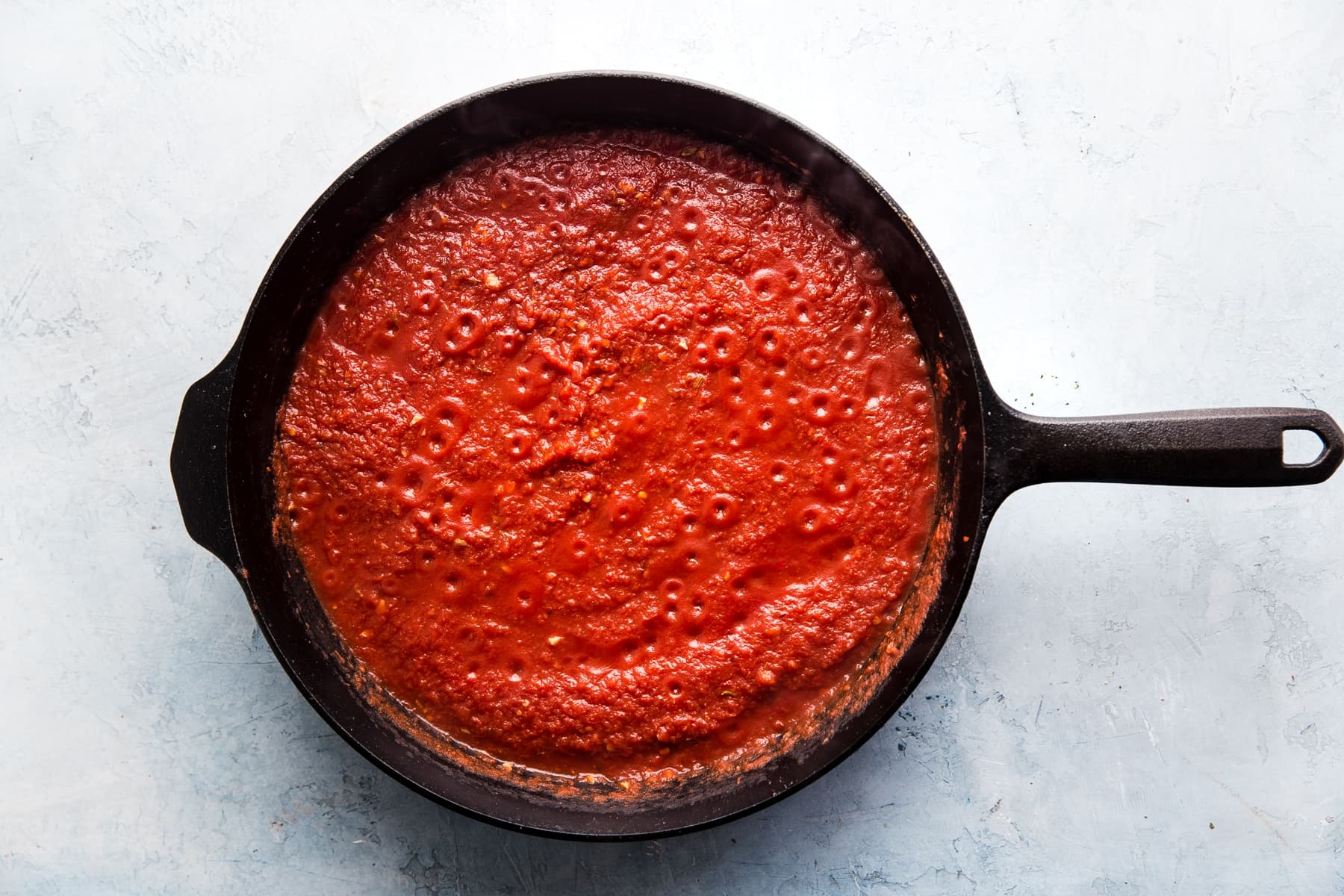 garlic, tomato paste and tomato sauce simmering in a cast iron skillet