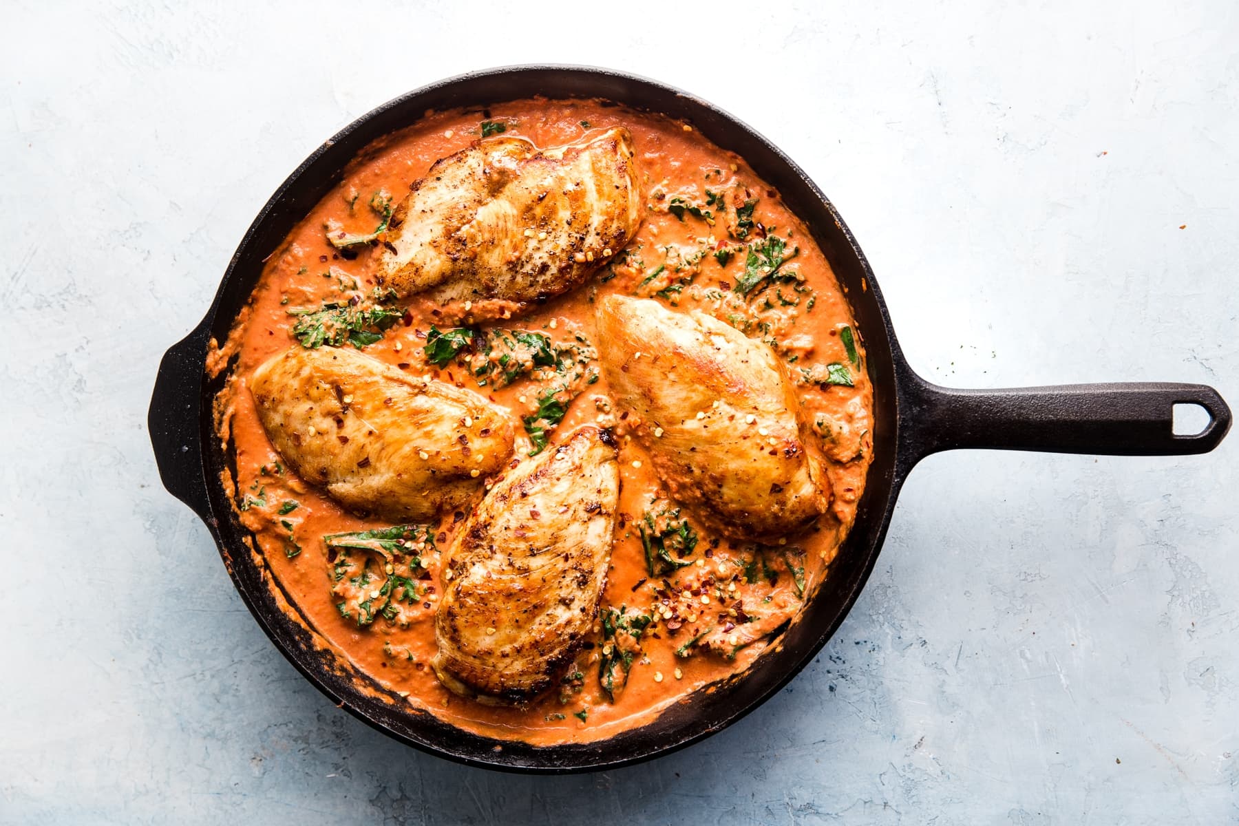 Creamy Tomato Chicken Skillet with kale and basil in a cast iron skillet