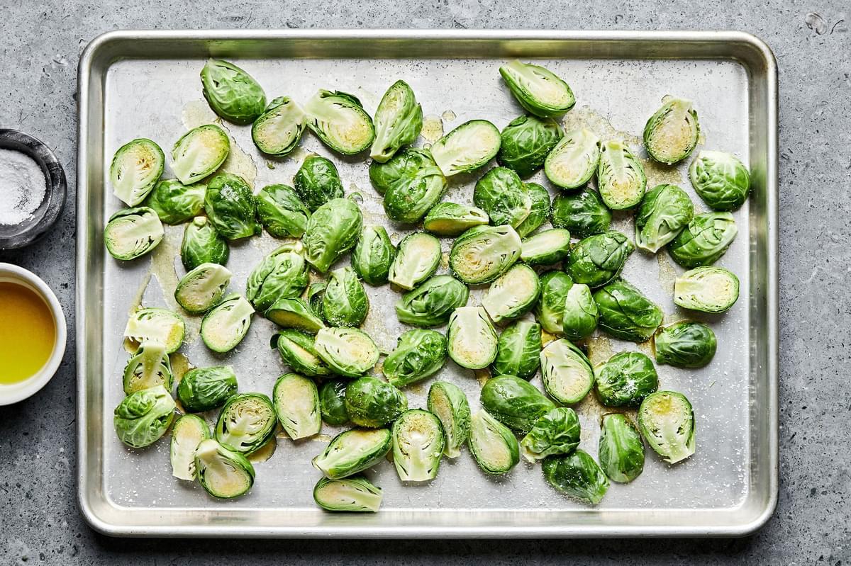 brussels sprouts cut in half tossed with olive oil and salt laying on a baking sheet