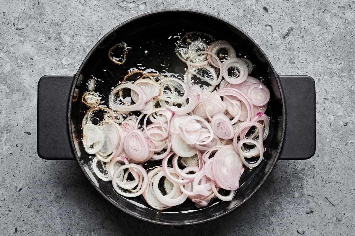 shallots being fried in vegetable oil in a large pot