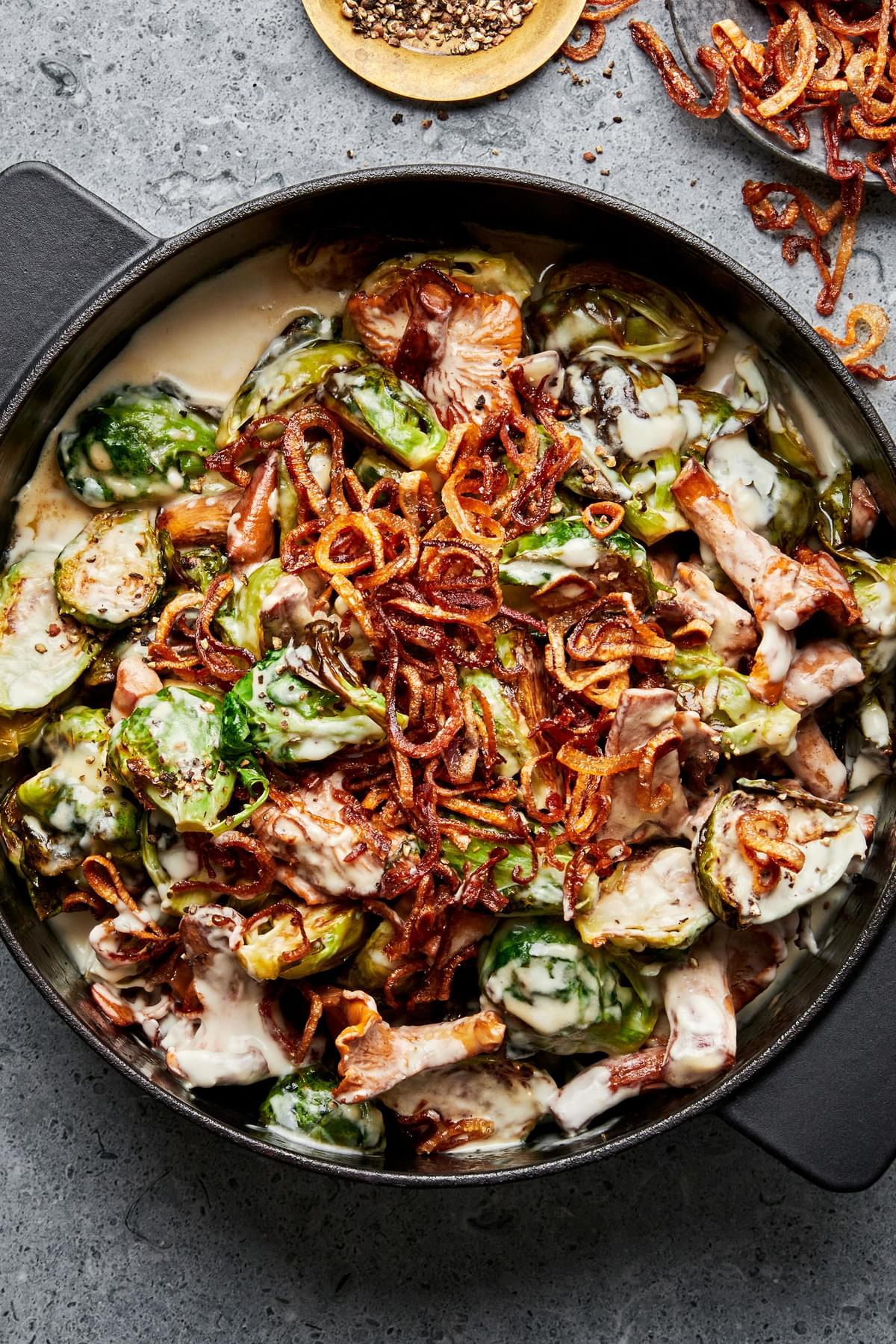 creamy brussels sprouts with wild mushrooms topped with fried shallots in a skillet