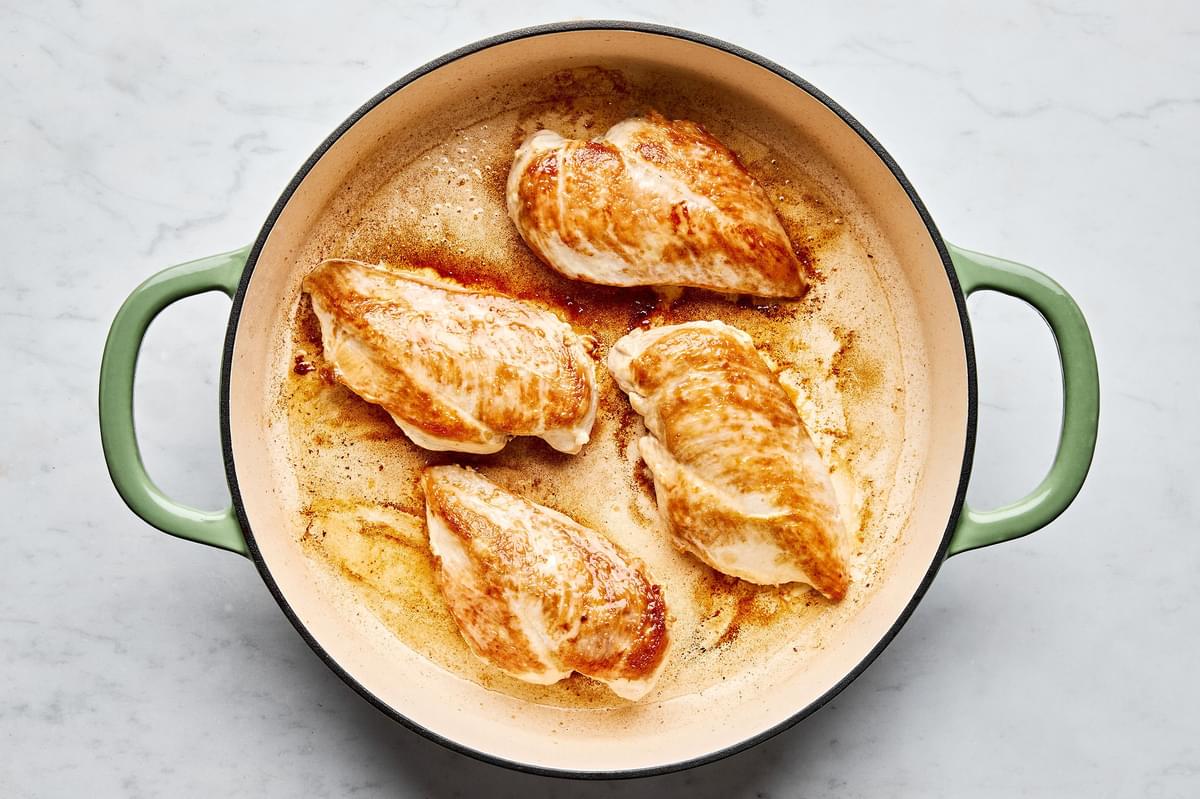 chicken breasts seasoned with salt being browned in olive oil in a skillet