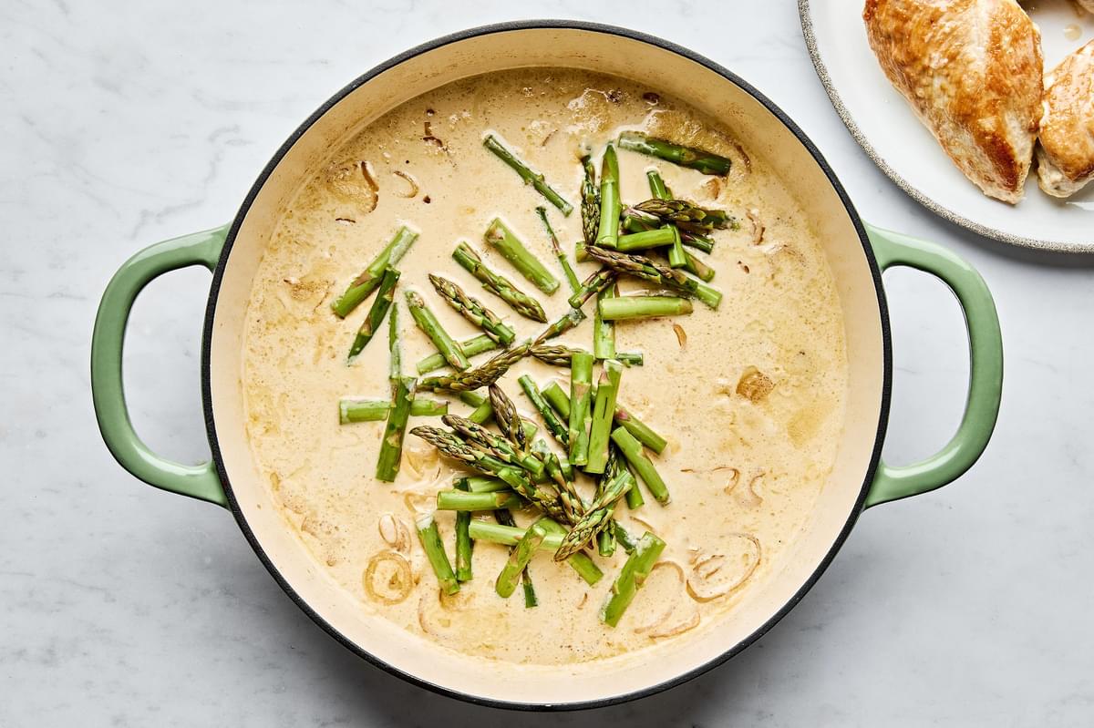 asparagus added to a skillet with cream sauce