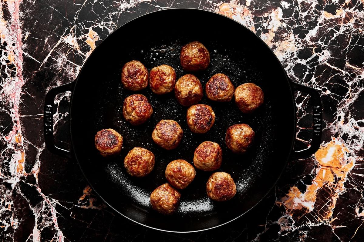 homemade turkey meatballs being browned in olive oil in a skillet