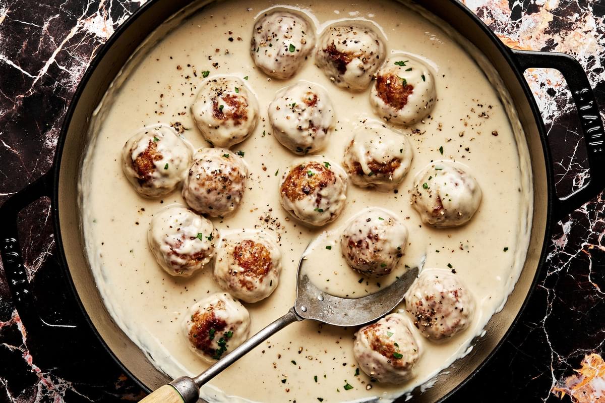 turkey meatballs being cooked in cream sauce in a skillet