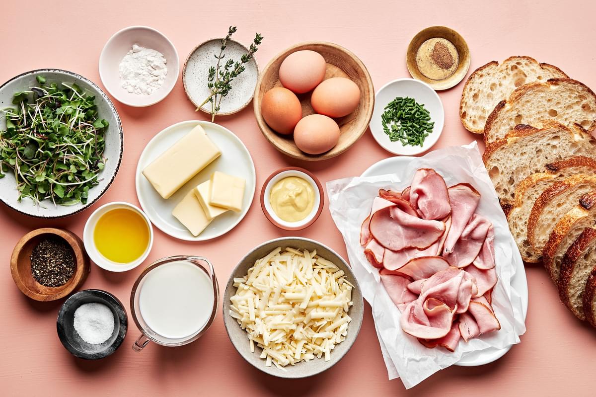 bread, ham, Gruyère, eggs, butter, chives, micro greens and ingredients for homemade  Béchamel sauce in prep bowls