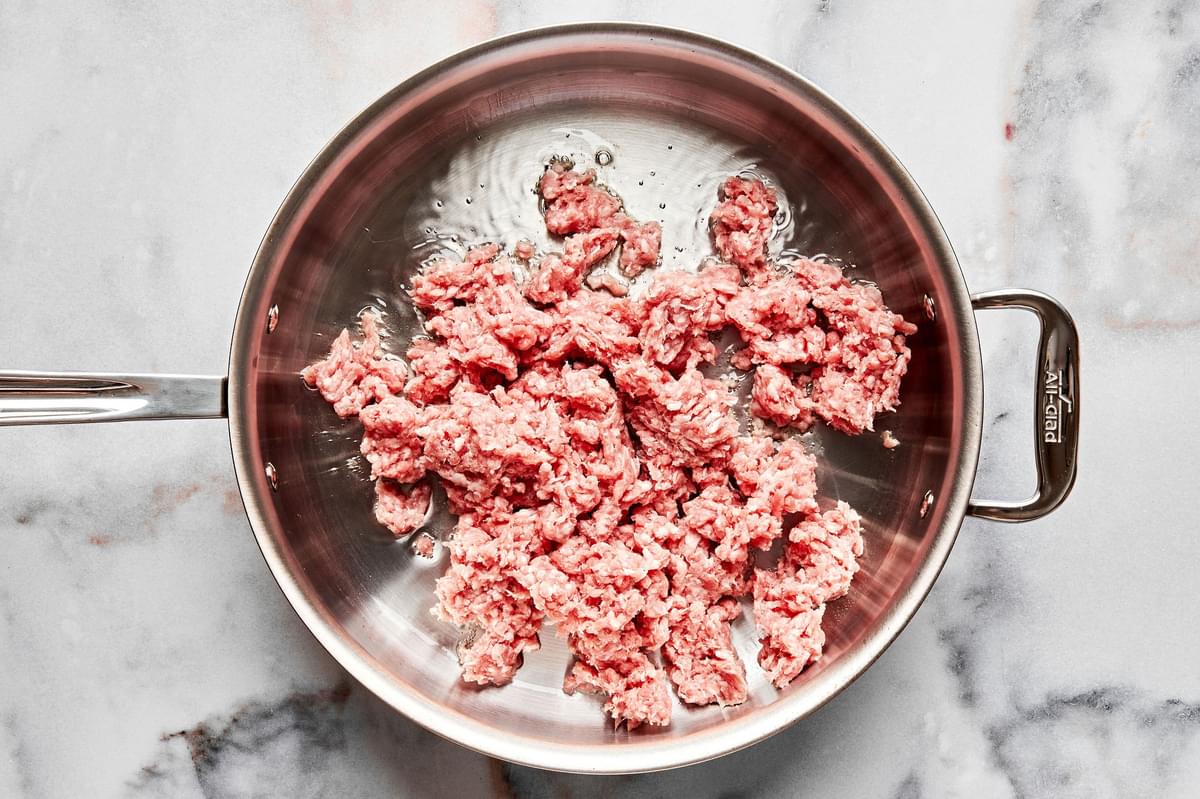 ground pork being cooked in vegetable oil in a skillet