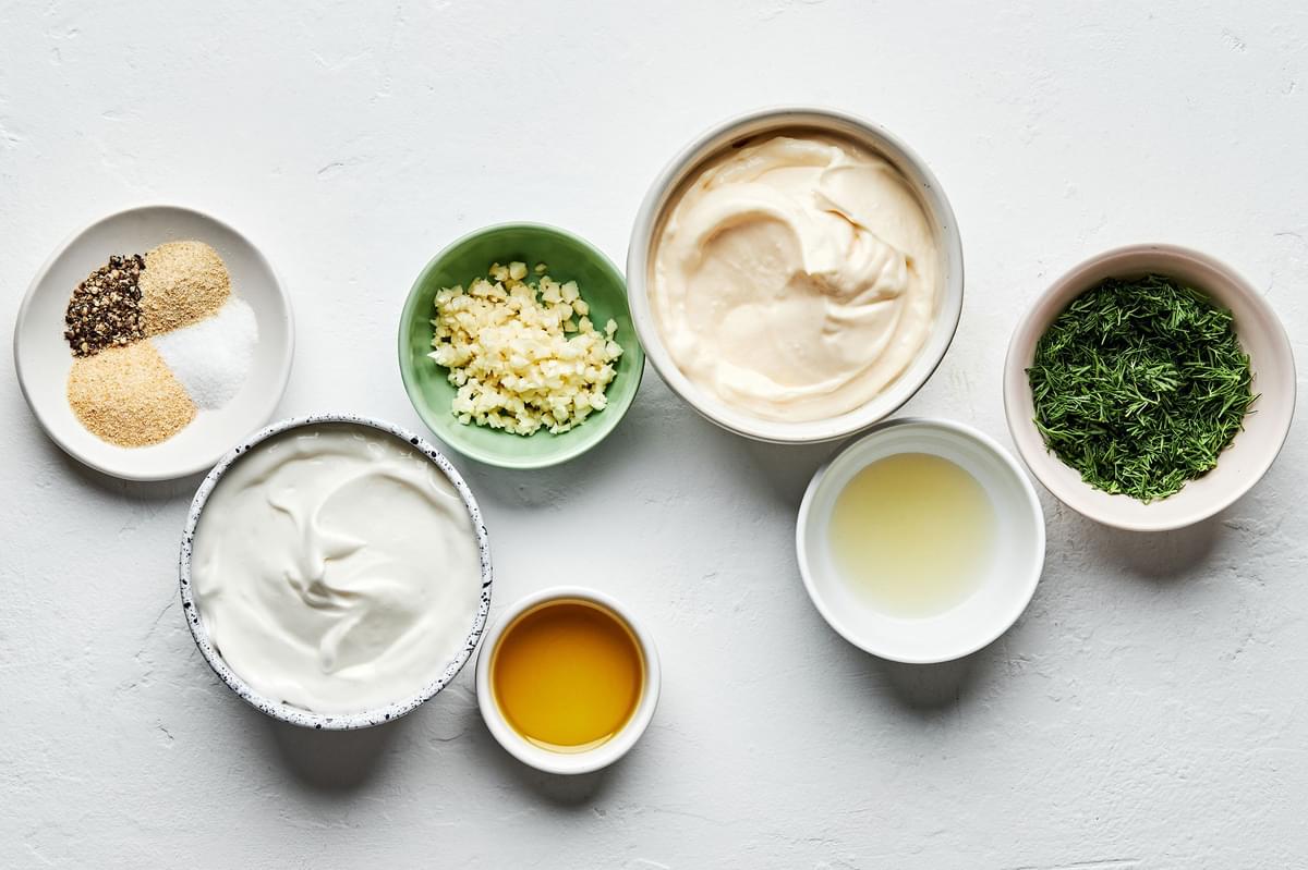 olive oil, mayonnaise, sour cream, garlic, fresh dill, garlic powder, onion powder, lemon juice, sea salt and pepper in bowls