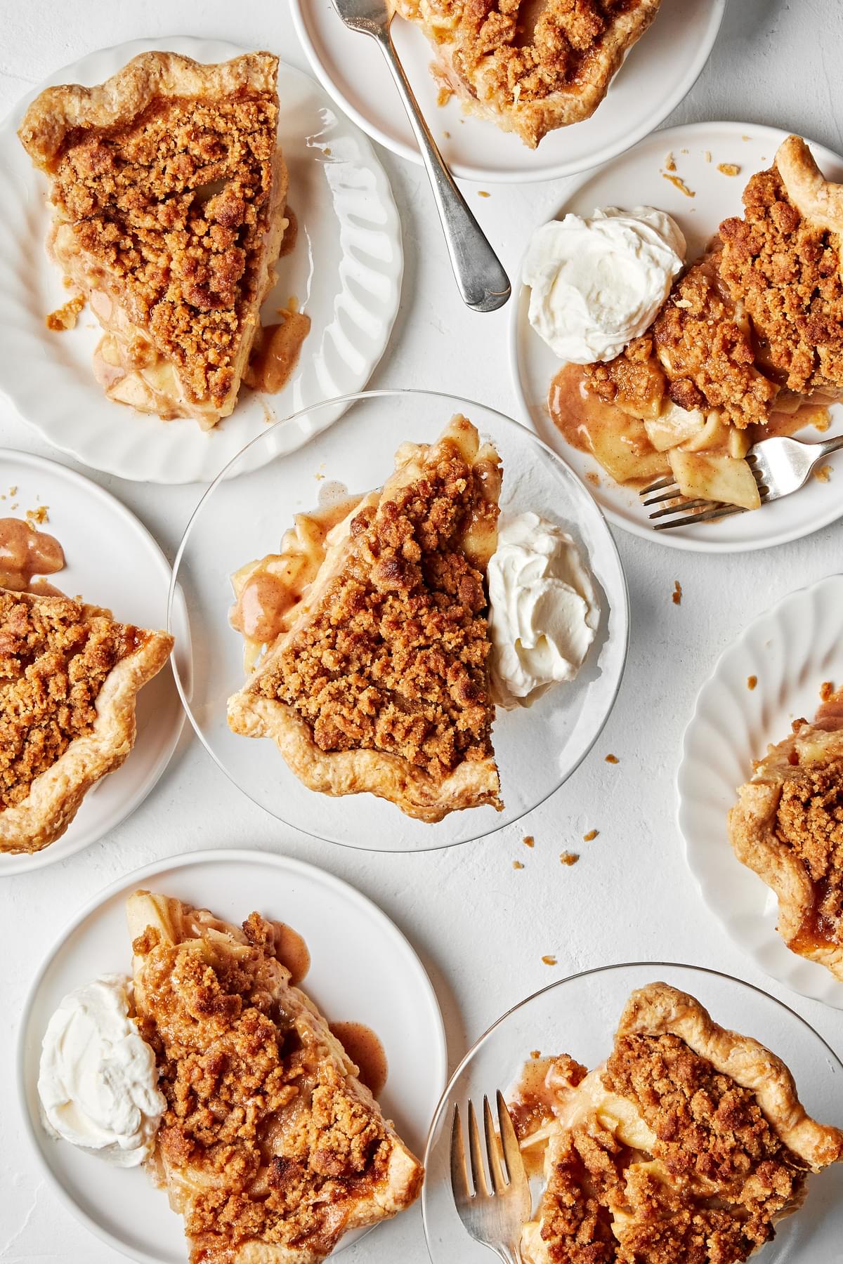 slices of homemade Dutch apple pie toped with dollops of whipped cream on plates