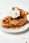 a slice of homemade Dutch apple pie topped with a dollop of whipped cream on a plate