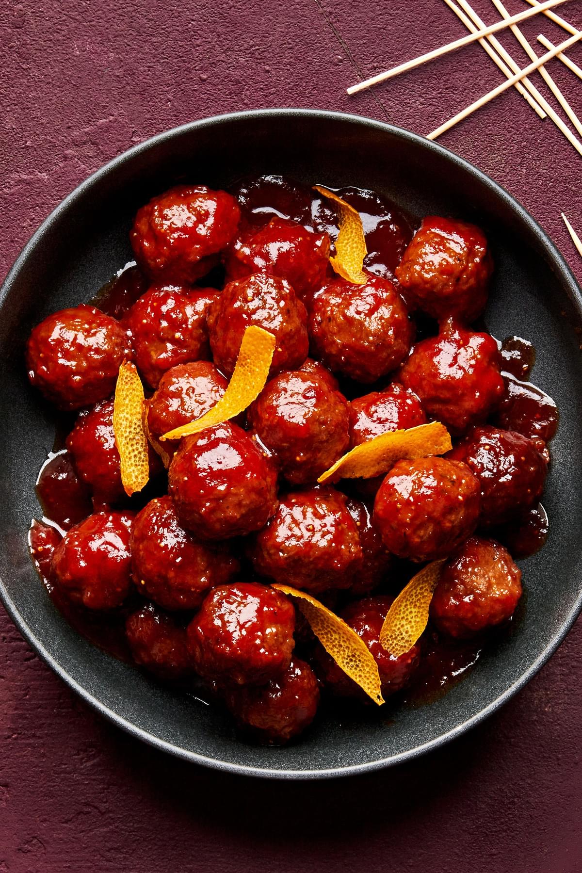 fig jam meatballs in a serving bowl made with fig jam, chili sauce and orange juice topped with orange zest