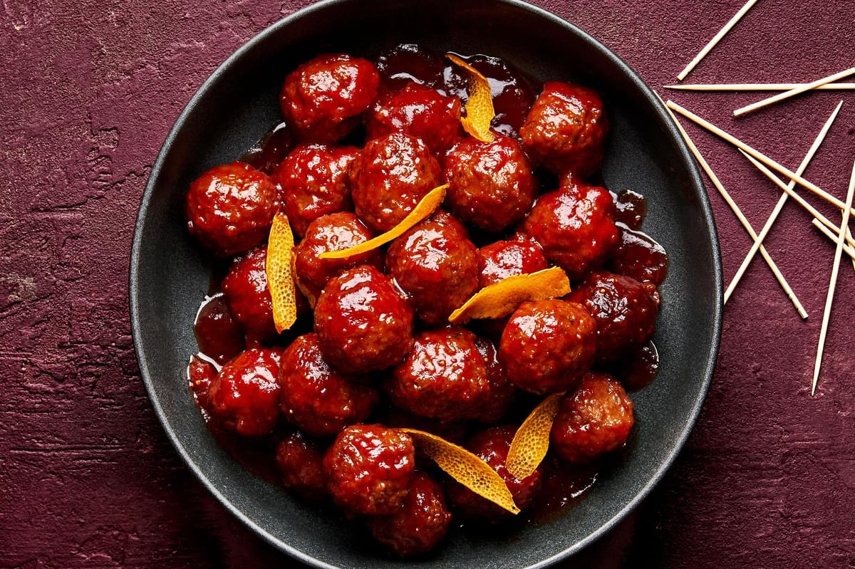 fig jam meatballs in a serving bowl, made with fig jam, chili sauce and orange juice topped with orange zest