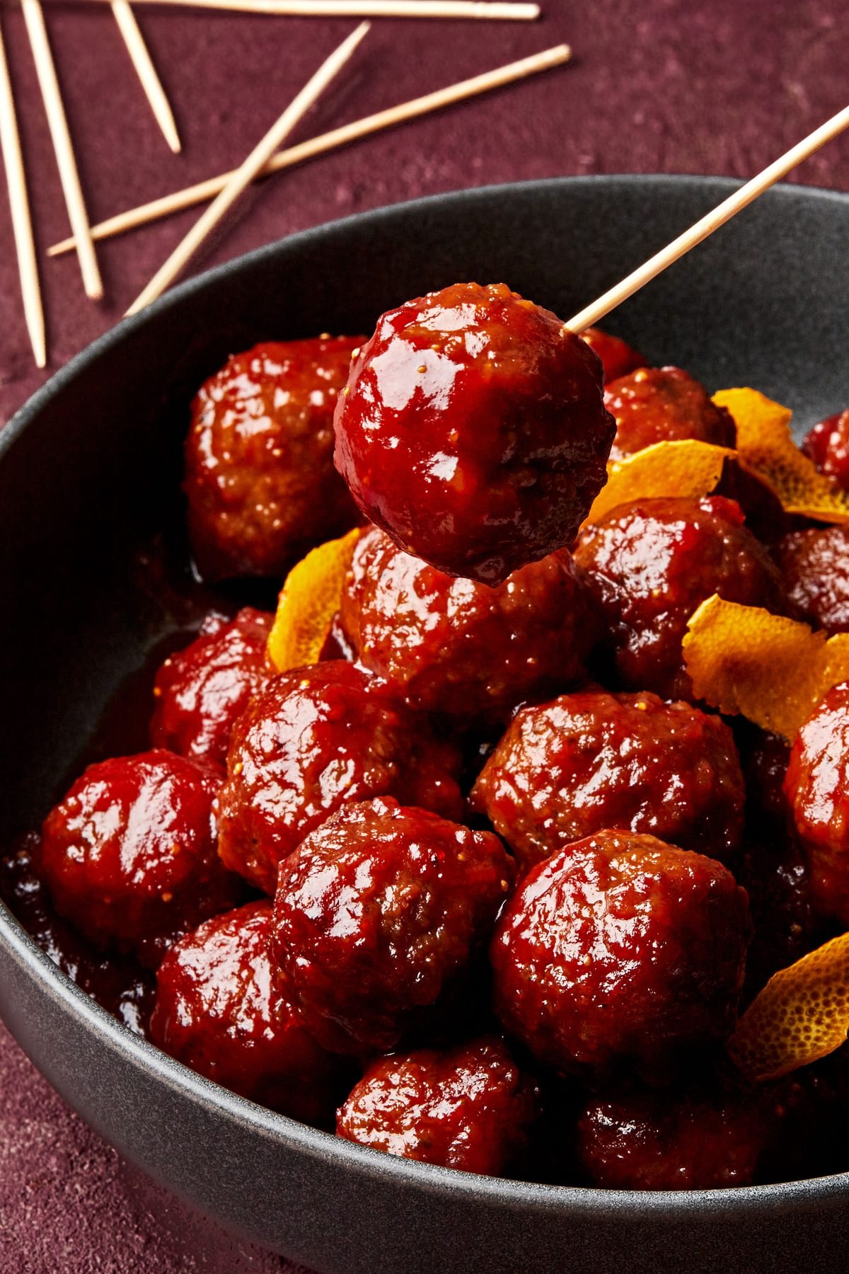 fig jam meatballs in a bowl made with fig jam, chili sauce and orange juice topped with orange zest