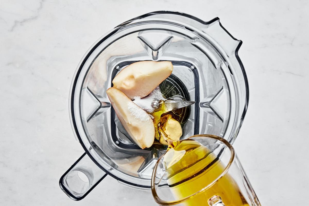olive oil, mustard, lemon juice, honey, salt, and pear being combined in a blender