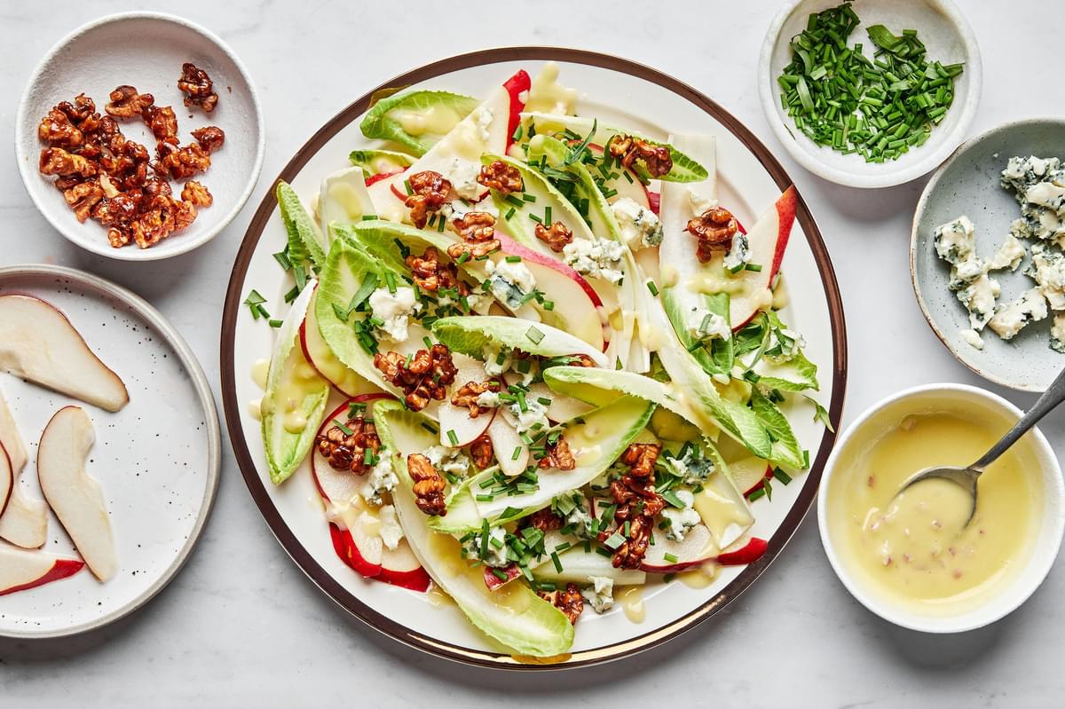An Endive and Roquefort Salad sprinkled with candied walnuts and fresh chives on a serving plate
