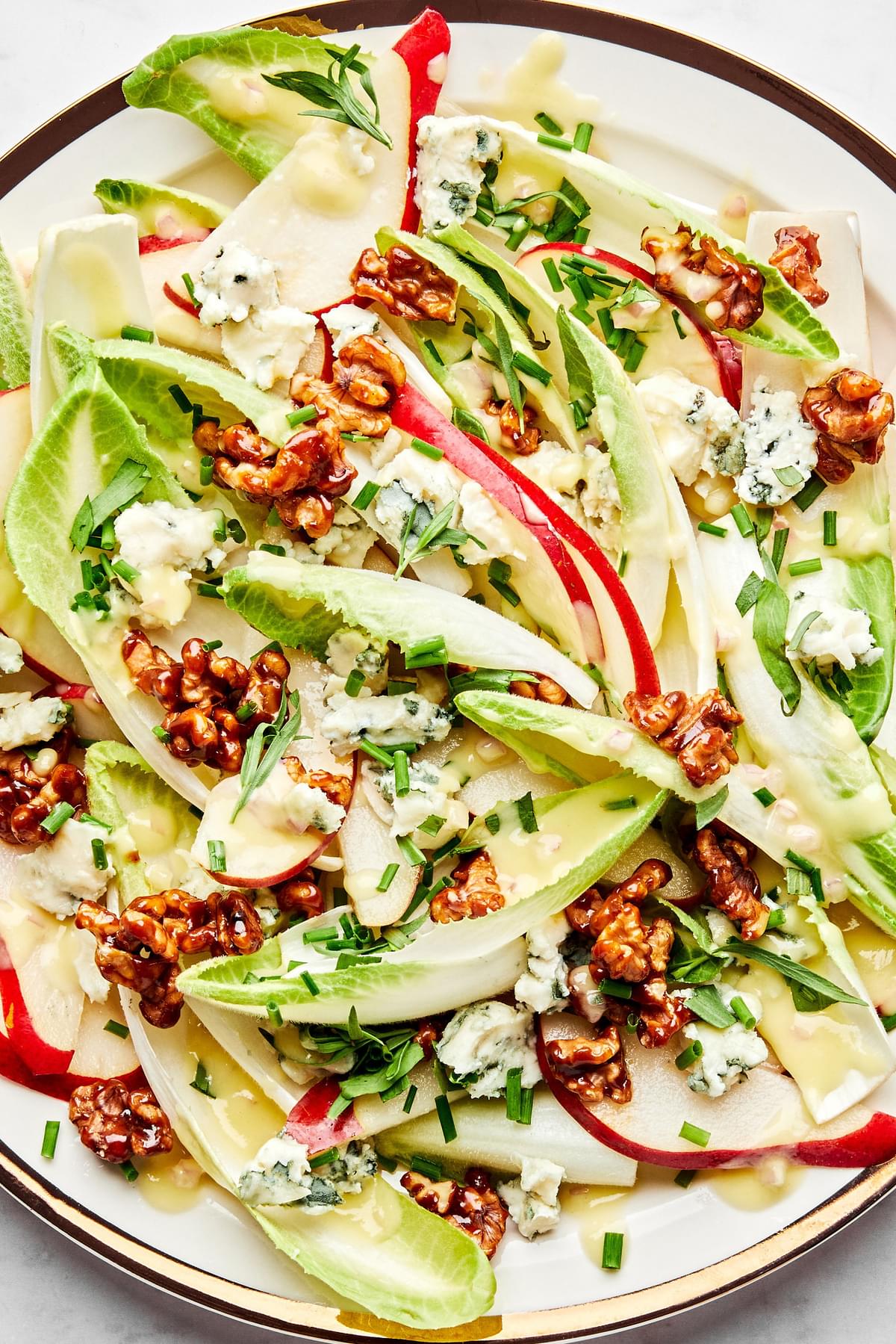 An Endive salad topped with pears, Roquefort, fresh chives, candied walnuts and drizzled with homemade pear vinaigrette