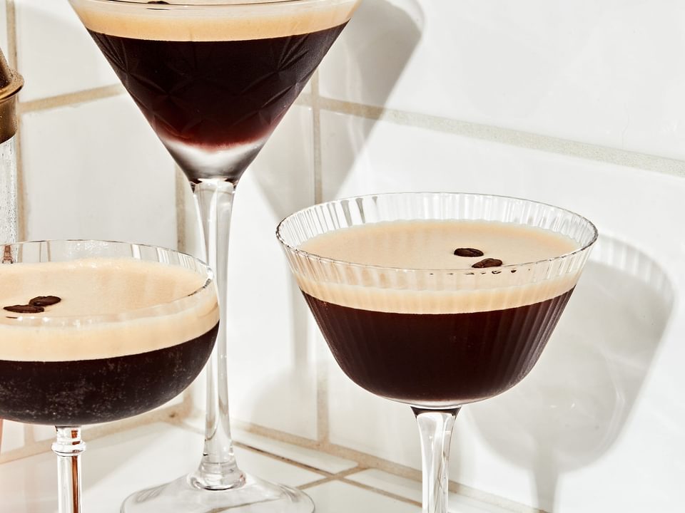 3 espresso martinis garnished with coffee beans on the counter