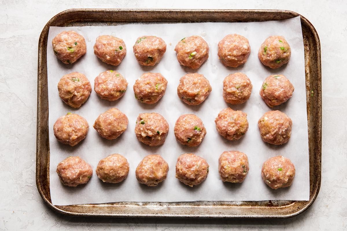 Asian inspired chicken meatballs on a baking sheet with parchment paper