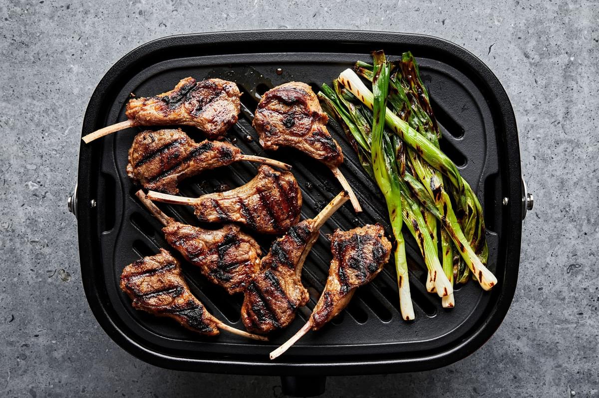 garam masala lamb chops and green onions cooking on a grill