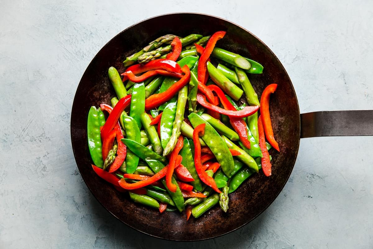 asparagus, red bell pepper and snow peas sautéed in a frying pan