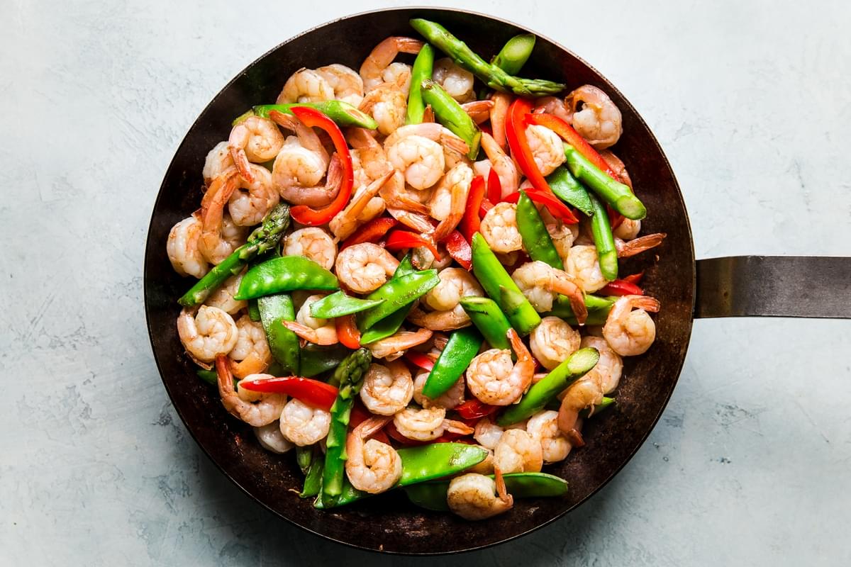 Garlic Shrimp Stir Fry in a pan wth asparagus, snow peas and red bell peppers