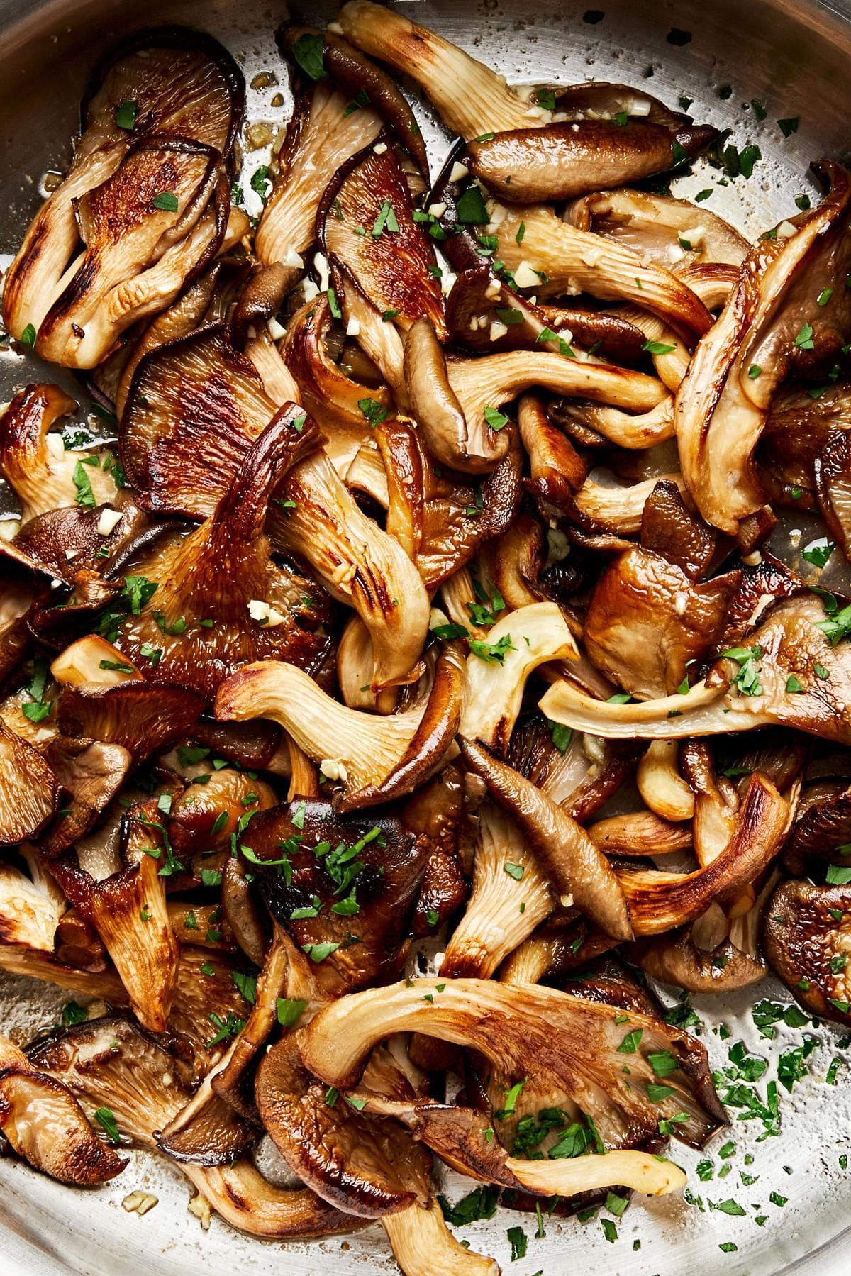 a skillet of garlic butter oyster mushrooms cooked in salt, olive oil, butter, garlic and sprinkled with fresh parsley